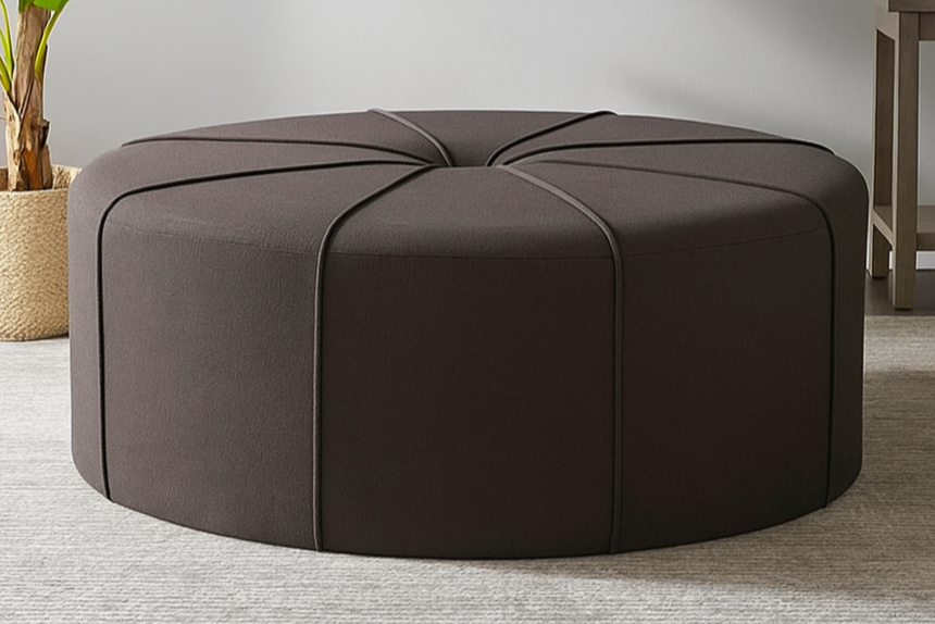 Brown ottoman in a living room with a plant and artwork on the wall.